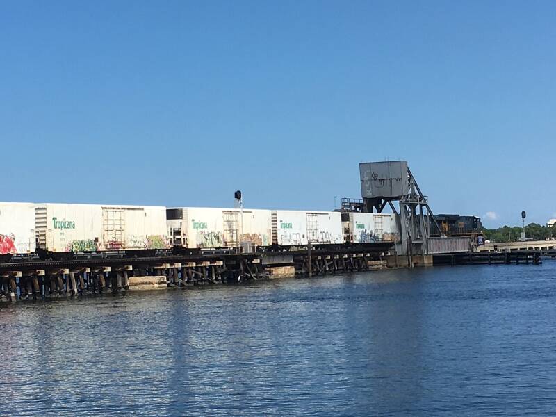 a locomotive pulling boxcars on a bridge 