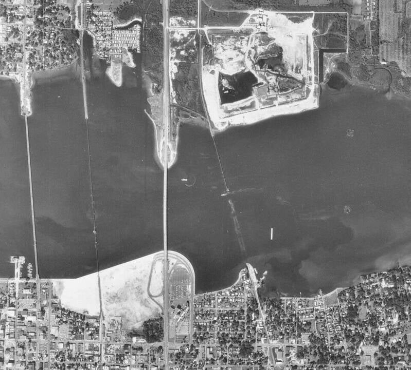 ariel photo depicting 2 shore lines and 4 bridges and/or remnants spanning the water from shore to shore