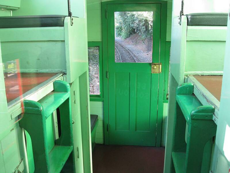 A view of the inside of a caboose with railroad track visible through one of its windows.