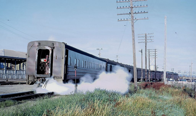 Brakeman obligingly blowing out the steam in CGW chair car -201 while unloading mail at U. P. Transfer in Council Bluffs, Iowa on August 8, 1962.