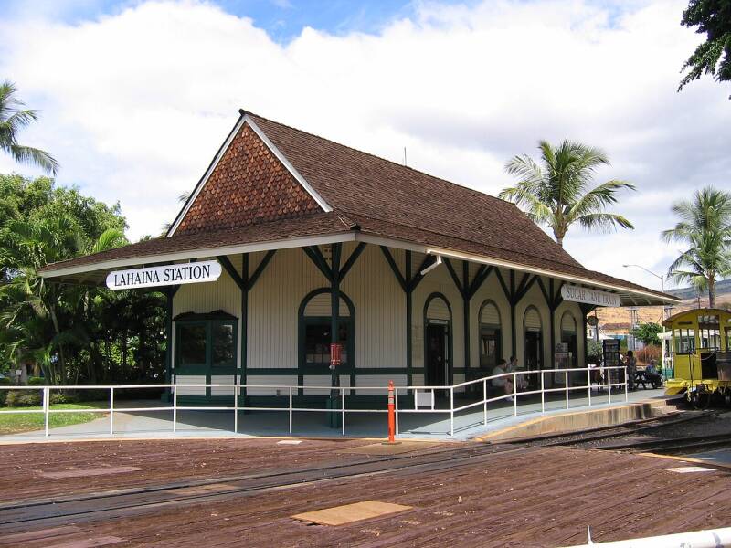 a vintage railroad depot sitting by some tracks by palm trees