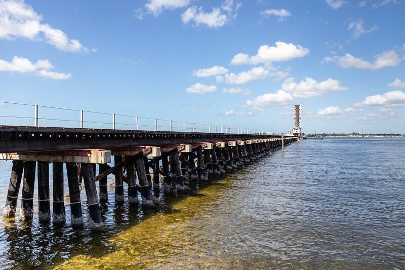 a long railroad trestle over a body of water with a raised bridge at the far end