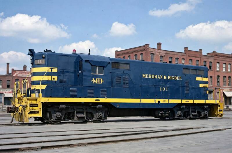 a freshly-painted older blue diesel locomotive with yellow trim