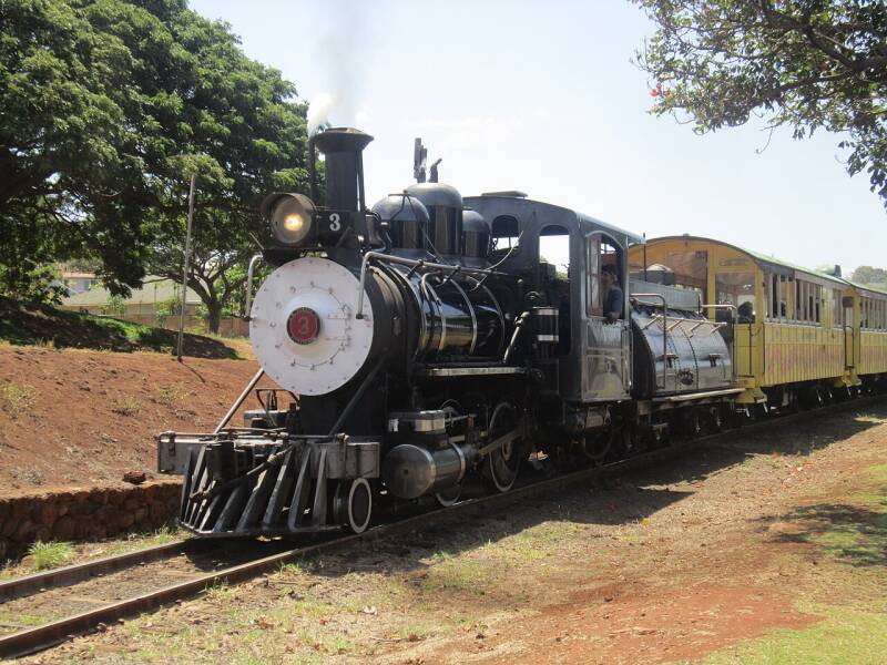 a small 2-4-0 steam locomotive pulling yellow passenger cars