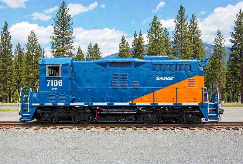 An older blue diesel-electric switching locomotive in front of some trees.