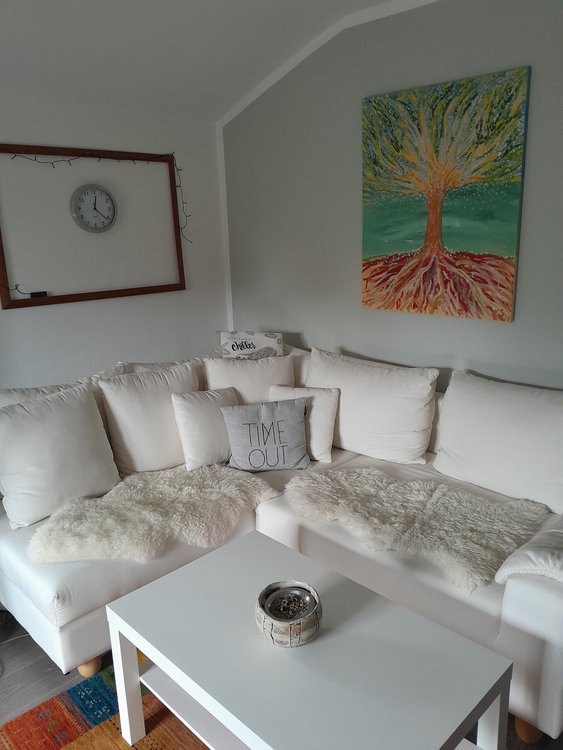 gemütliches Wohnzimmer mit heller Couch und Lebensbaum