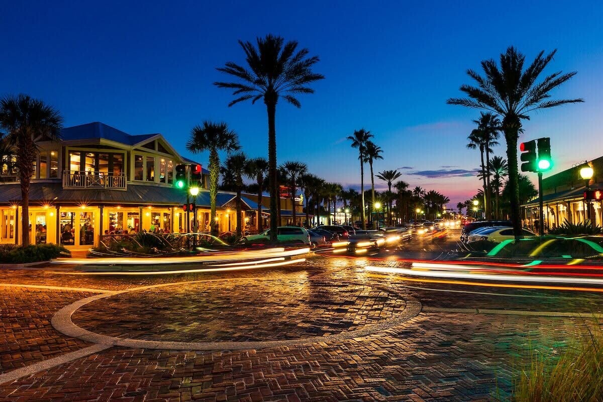 Coastal shopping district at dusk with palm trees and illuminated storefronts in the Atlantic and Neptune Beach area