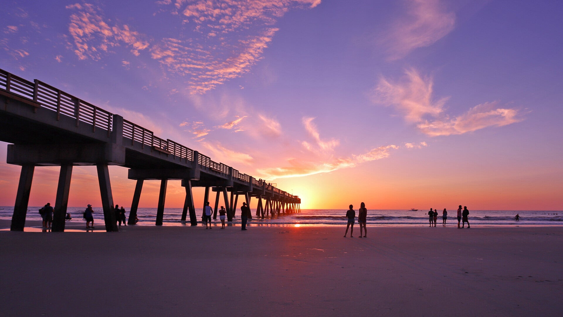 Jacksonville Beach Pier at sunset with visitors walking along the Atlantic shoreline