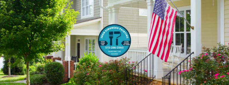 Yellow houce with american flag on front porch.