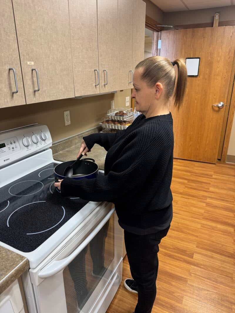 Image of a female stirring contents of a pot on the stove in the kitchen with her shoulders relaxed.