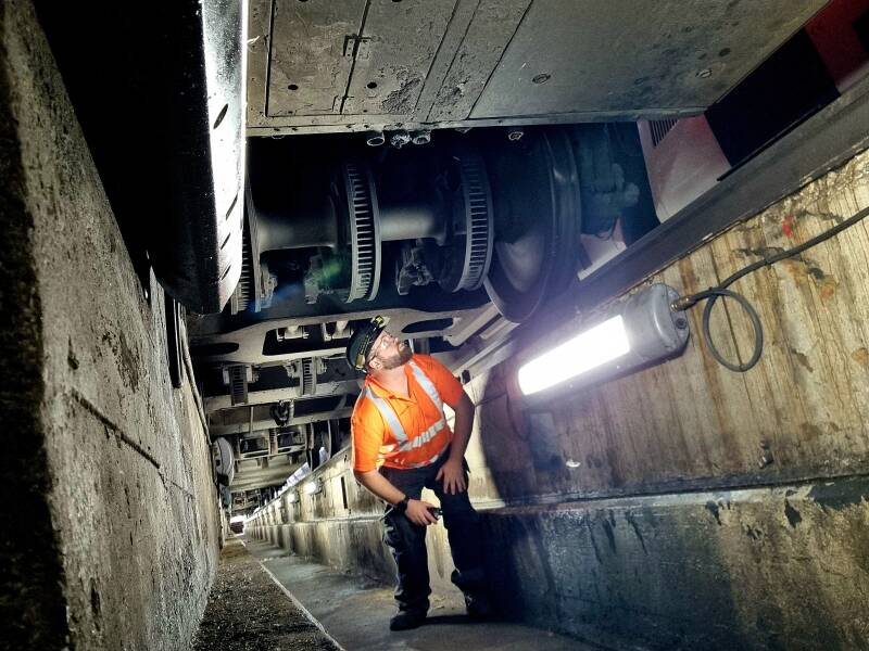 Rail engineer working beneath a train in a depot inspection pit