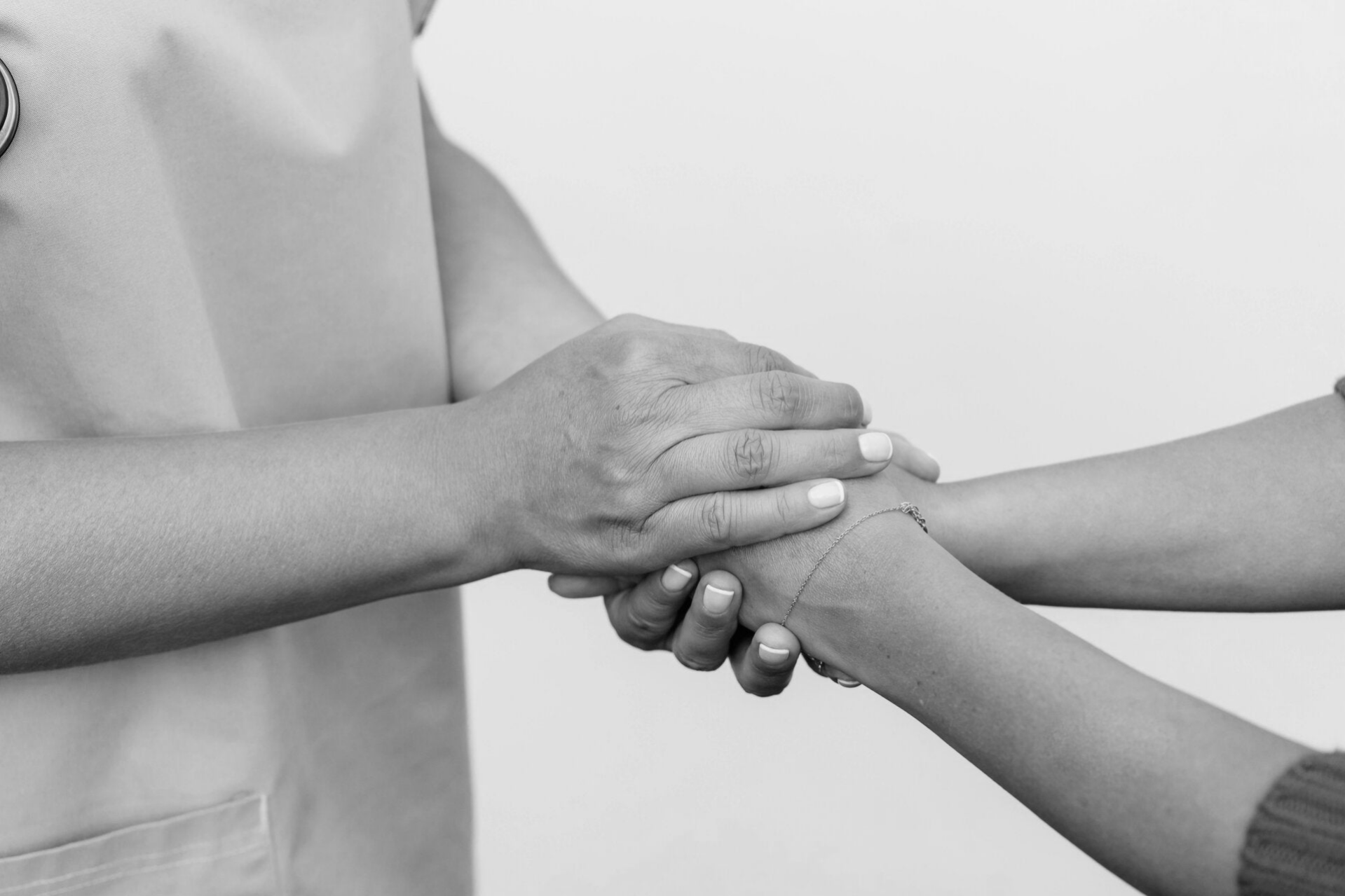 Picture of healthcare worker cupping hands around a patient's hands. Black and white photo. Evokes a sense of compassion and care.