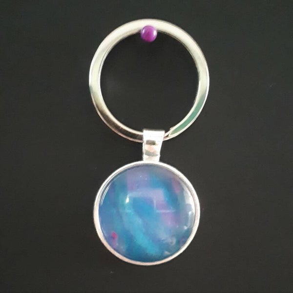 Silver-coloured keychain hanger with unique pink/purple accented stone Product # keySCMPcab1