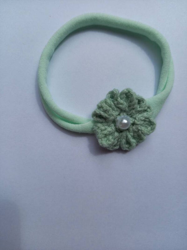 Een mint groen nylonhaarbandje met een mintgroen bloemetje