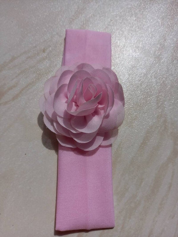 Een breed roze haarbandje met grote bloem