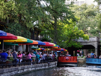 San Antonio Texas riverwalk with boats and diners under umbrellas