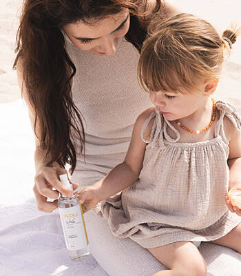 Moeder en kind op het strand met flesje Magnesium Kinderolie