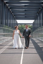 Bruidspaar loopt op strakke moderne brug, stedelijke trouwreportage.