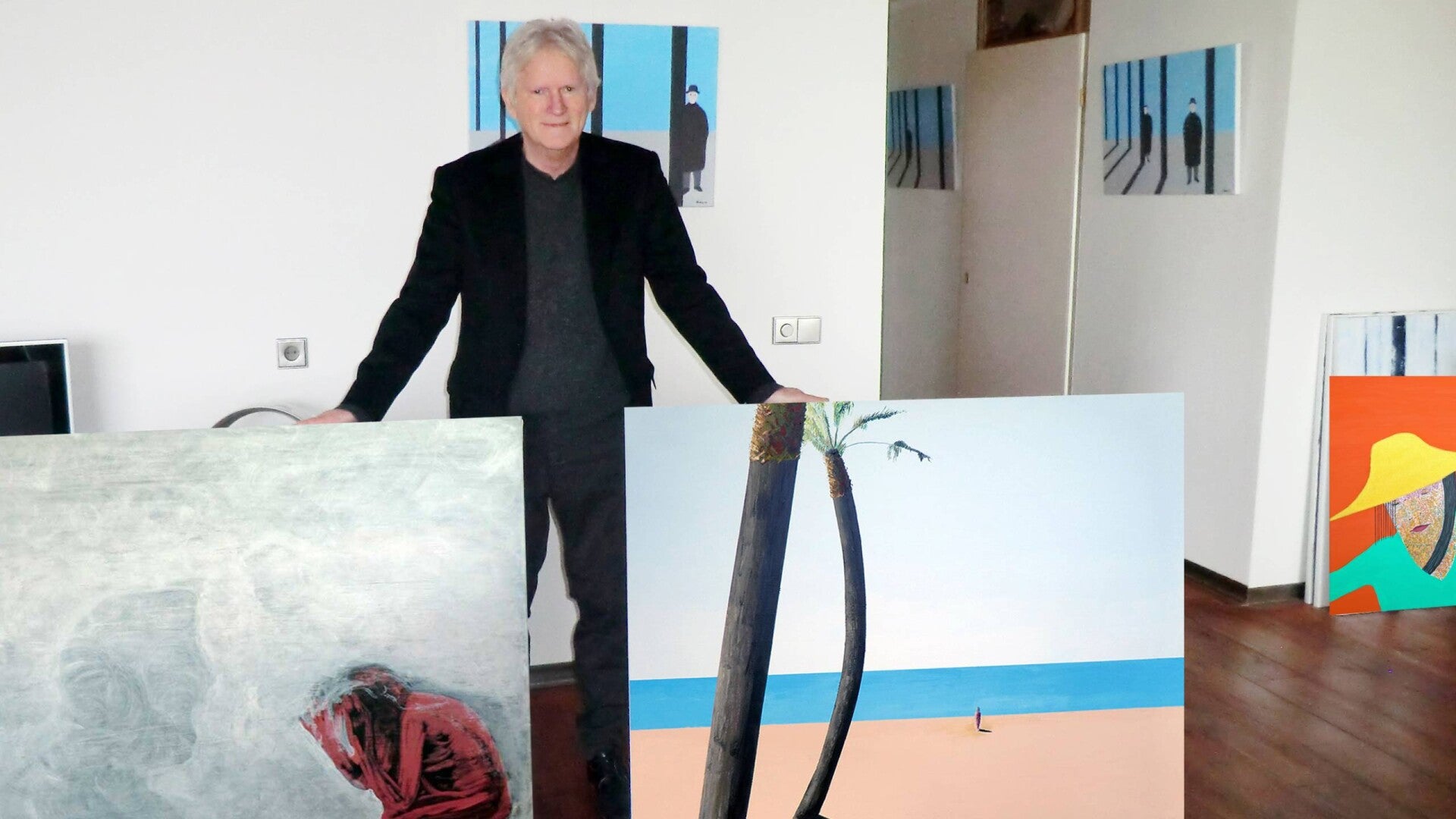 kunstschilder Geurt tussen zijn schilderijen