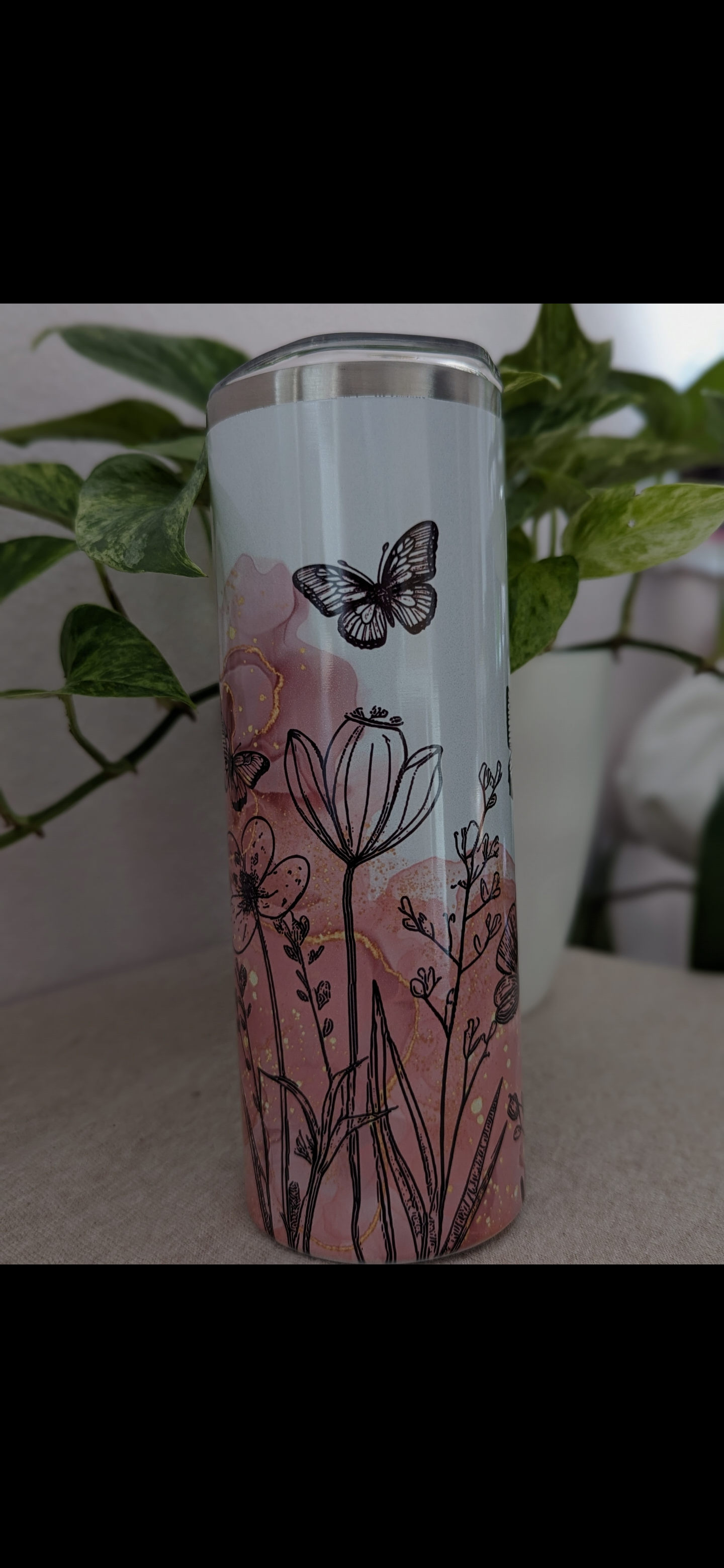 Sublimierter Thermobecher mit Schwarzen Blumen, einem schwarzen Schmetterling und einem Watercolor Hintergrund der von Rose ins weiße Übergeht.