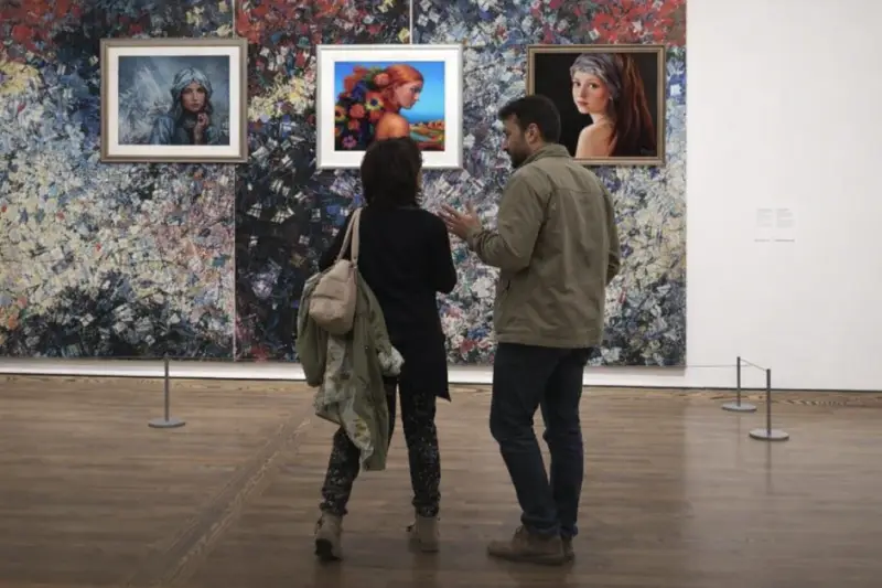 Two visitors are at the Gqllery. The portraits made by ElenaG on the walls.