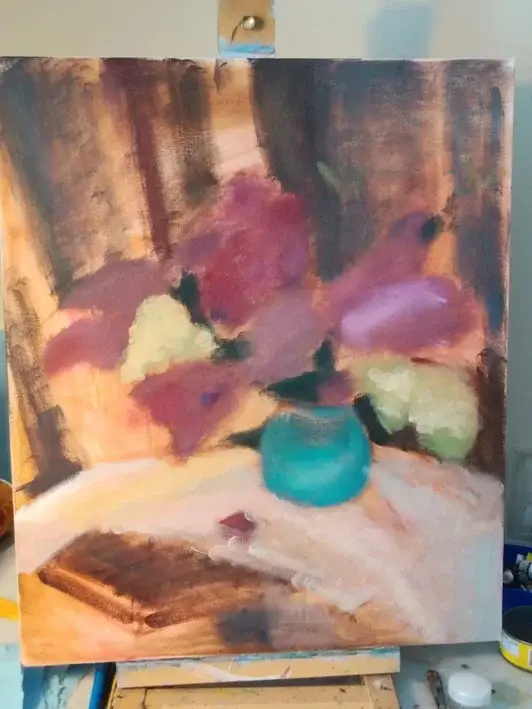 The easel with a canvas with a beginning painting process of a still life of lilac.
