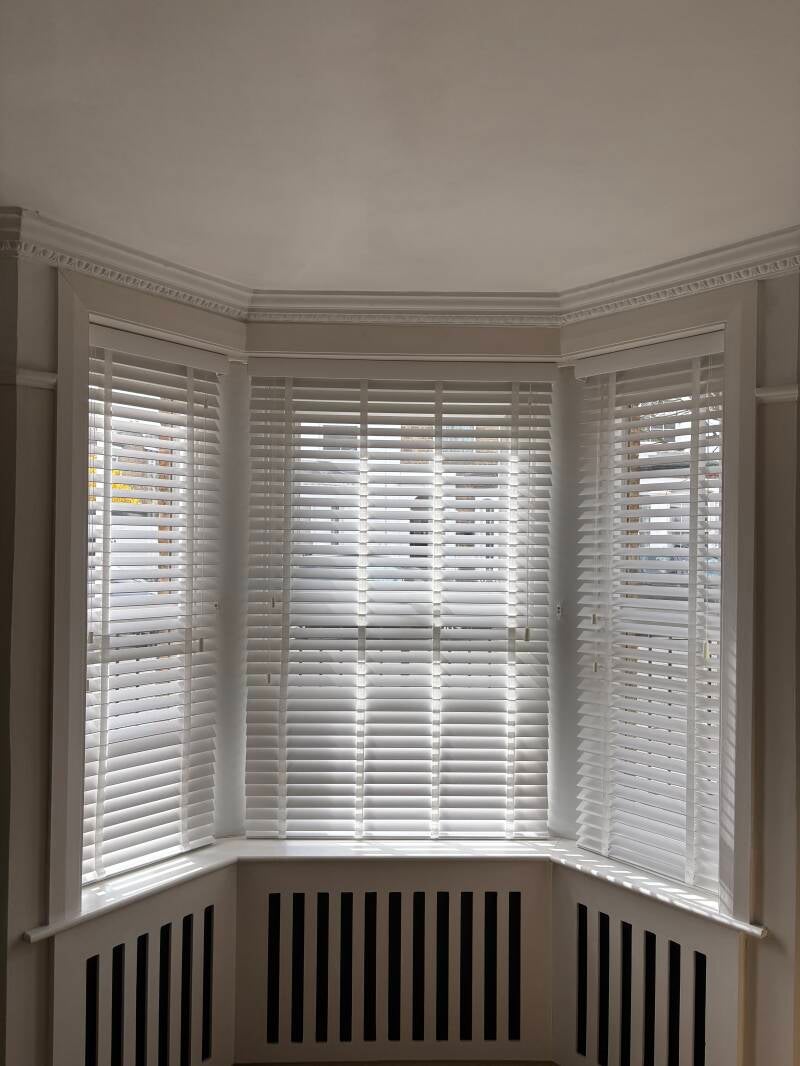 White faux wood venetian blinds perfectly installed in a living room bay window in Margate, Kent.