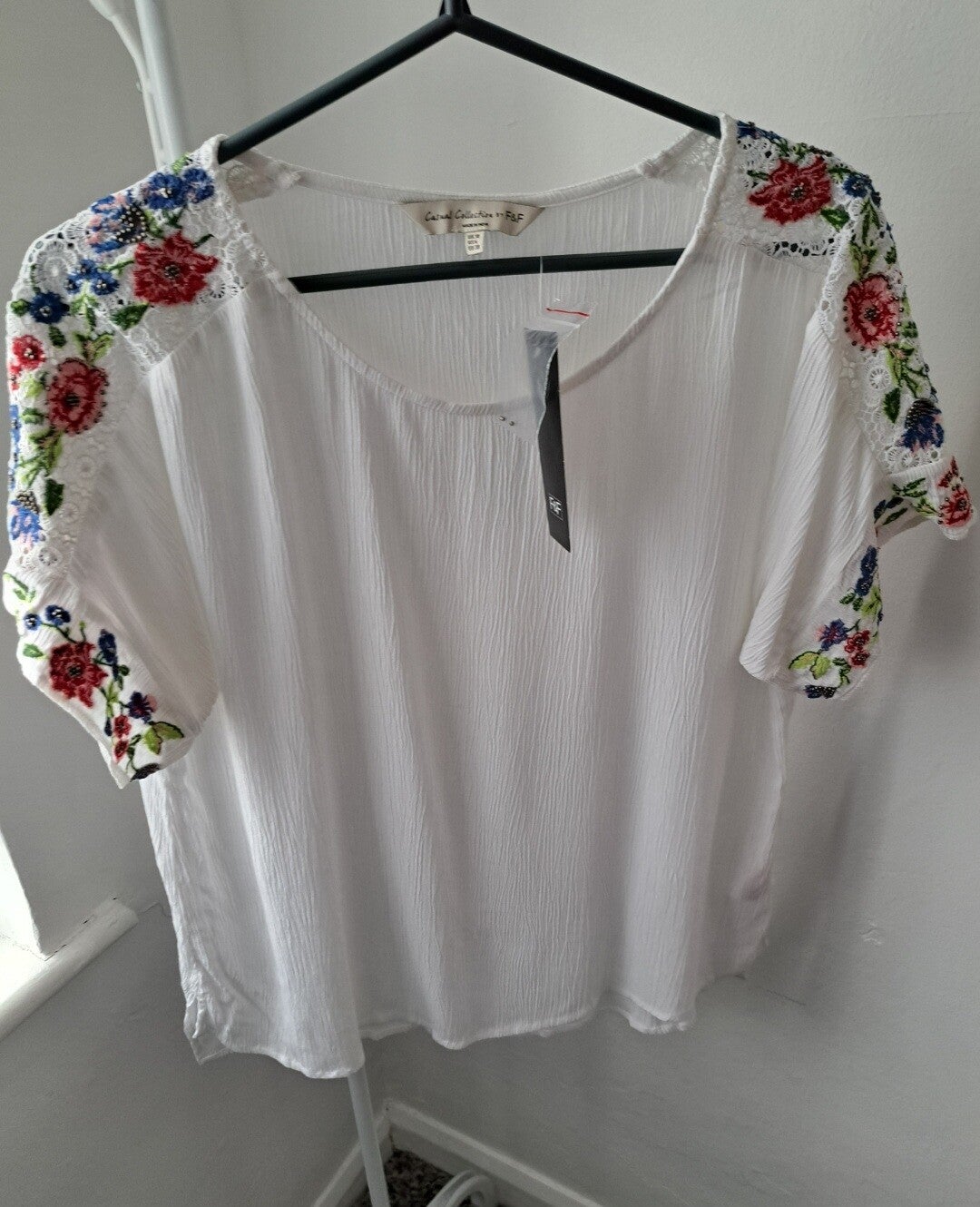 White short sleeve top with floral decoration on the shoulders. Size 10 by F&F