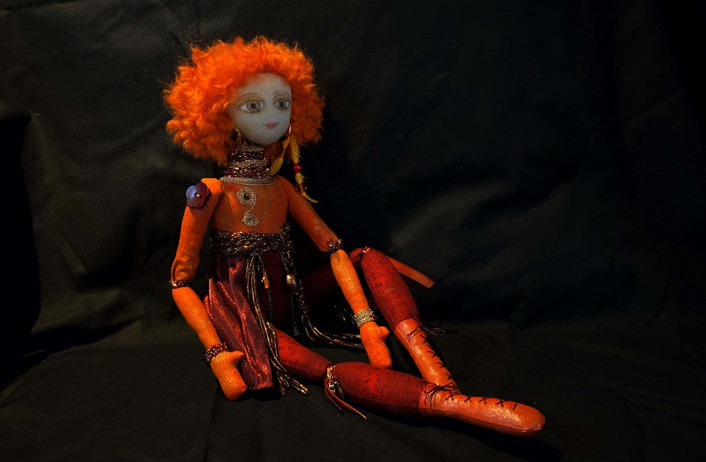 A beautiful beaded cloth art doll in gold , orange and red.