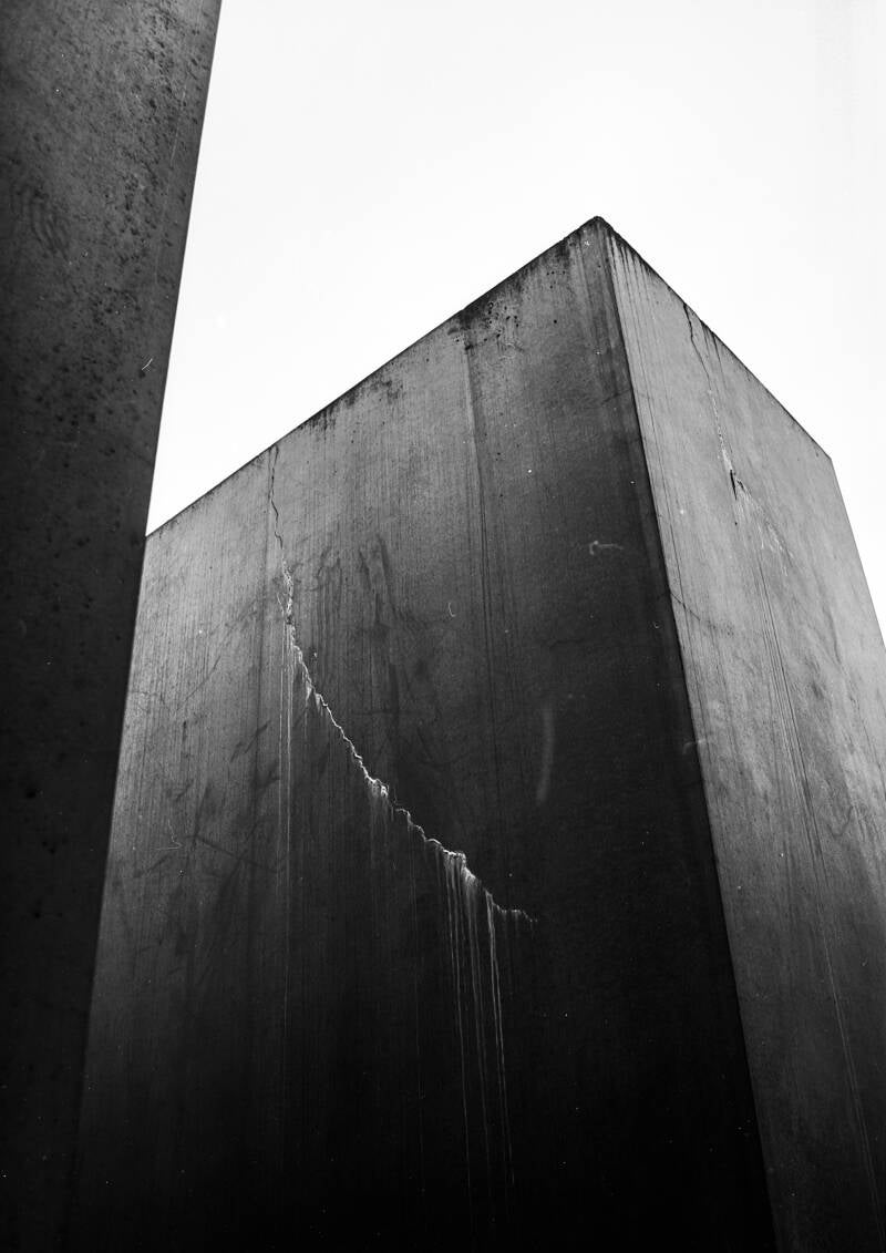 Analoge zwart wit foto gemaakt met een 35mm kleinbeeld camera; detail van het Holocaust monument in Berlijn met een scheur waaruit sporen van lekkage lopen; een dreigend beeld