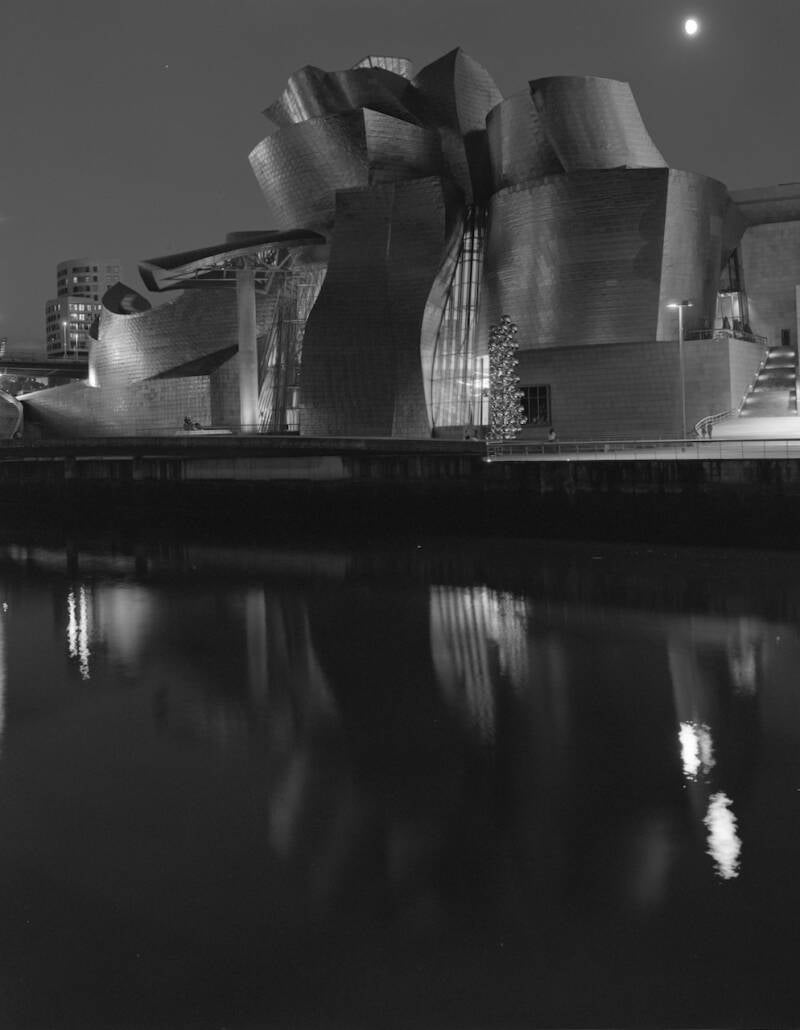 Analoge zwart wit foto gemaakt met een 4x5" Tachihara grootformaat camera; het Guggenheim museum in Bilbao, 's avonds met een volle maan en weerspigeling in het water