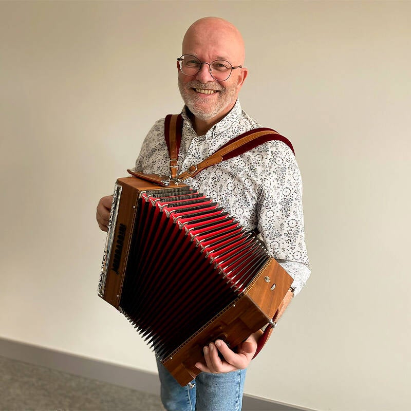 Rein Mebius is muzikaal leider, virtuoos op de trekzak, speelt cajon en djembe en zingt tweede stem