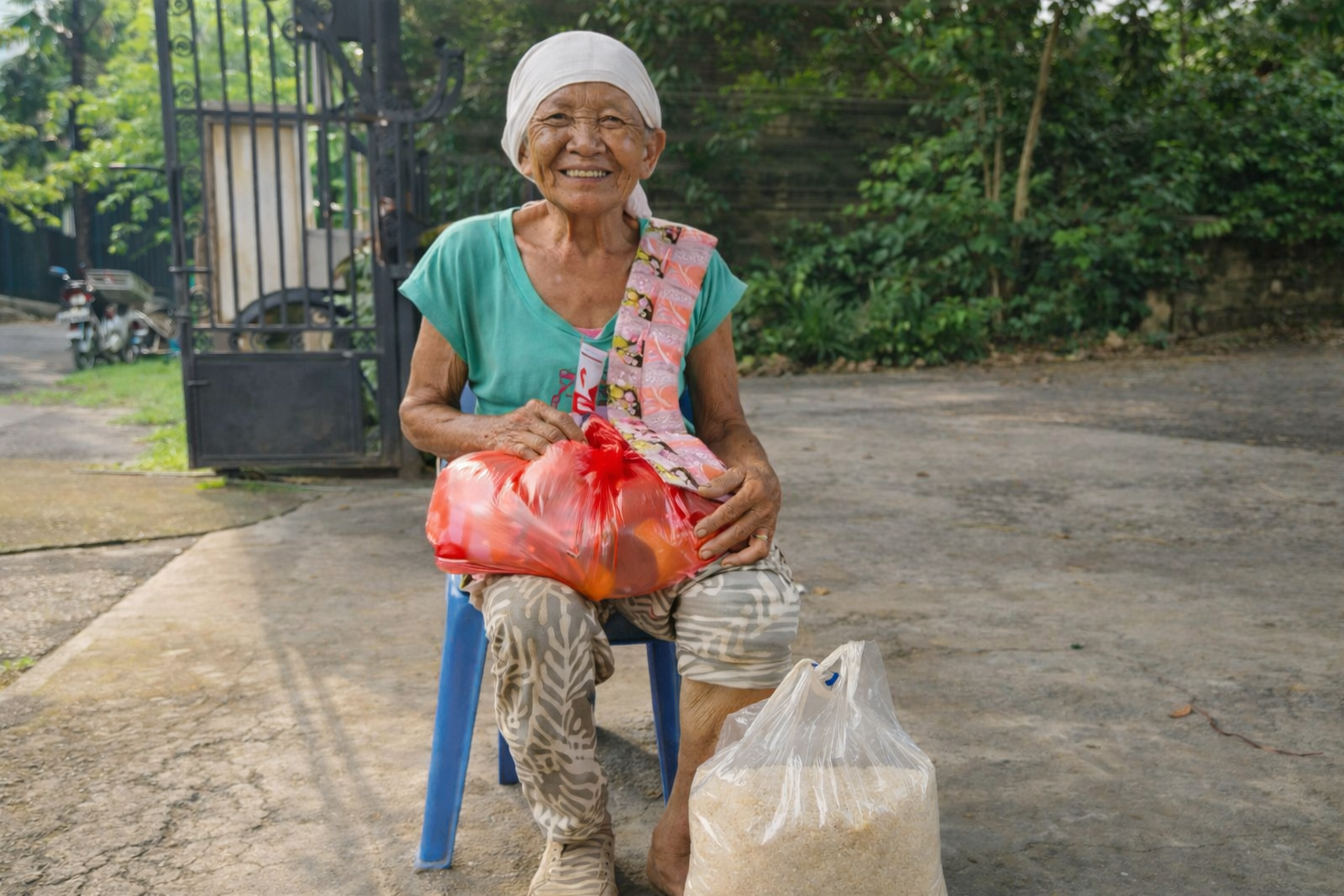 Bali Family Foundation food parcel given to Dadong sitting on a chair. Bali charity. BFF