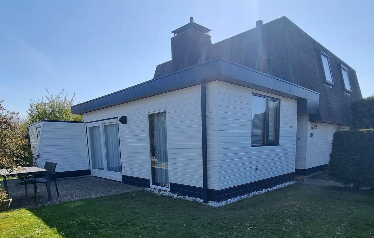 Vakantiewoning met strak wit geschilderde gevels en donkere kozijnen in de zon