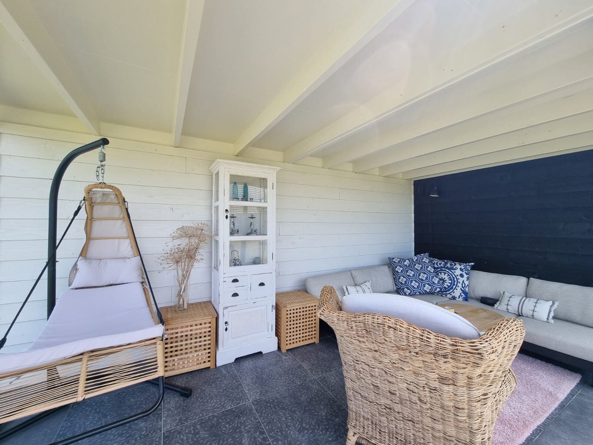 Veranda met wit geschilderd plafond, balken en houten wanden