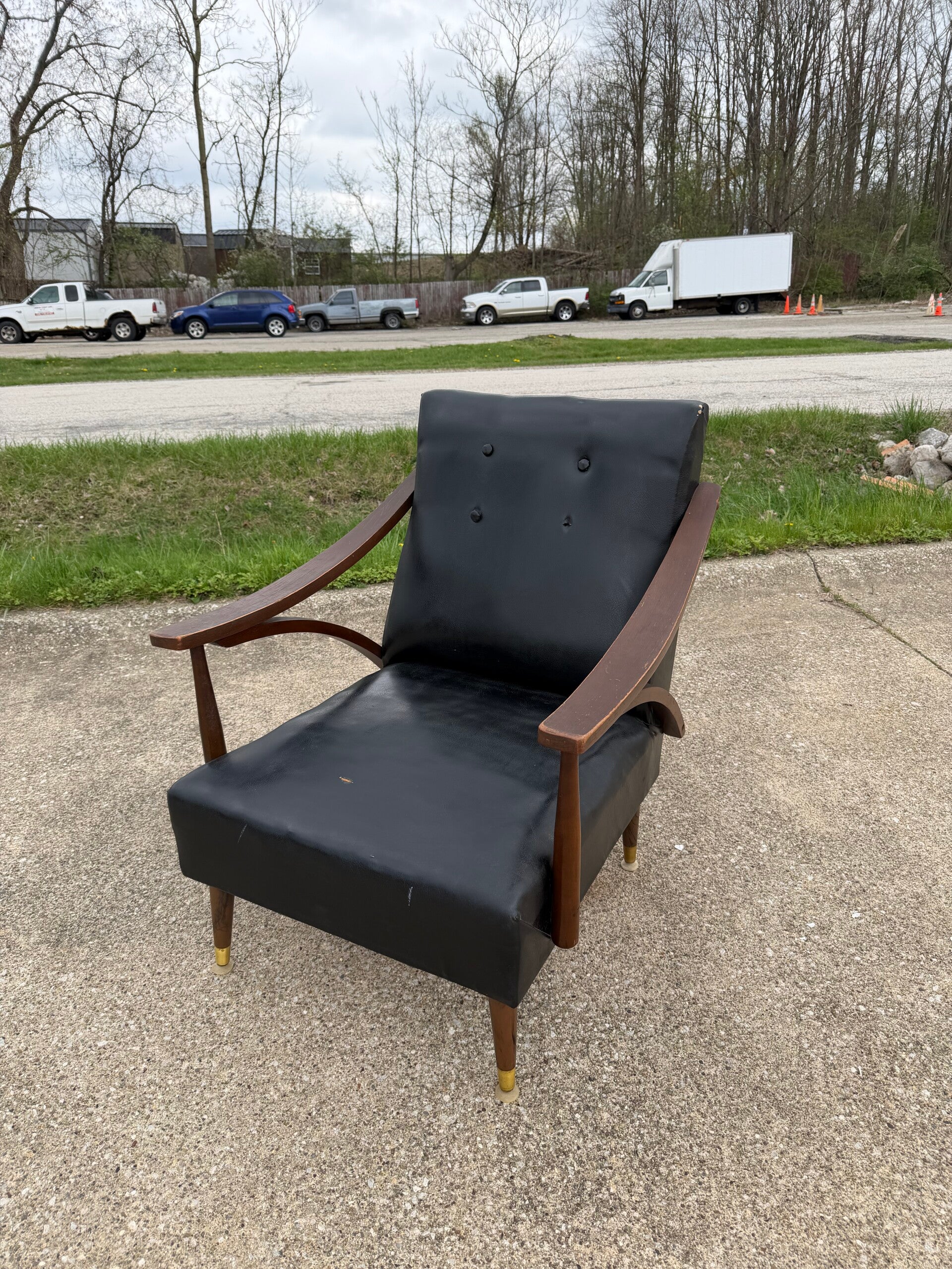 Mid-Century Modern armchair featuring wood armrests and black upholstery