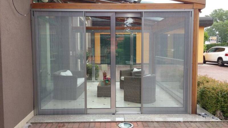 Zanzariera plissettata Briller installata su veranda con grandi aperture scorrevoli, soluzione su misura per protezione e comfort senza ingombro