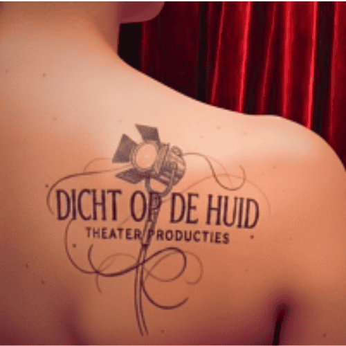 Logo van "dicht op de huid theater" tattoo op de rechter schouder met naam en theaterlamp