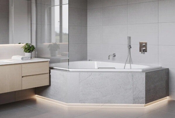 The image showcases a contemporary bathroom featuring a stylish corner bath installation, complemented by modern floor and wall tiling. This luxurious space exemplifies high-quality renovations, perfect for anyone considering a complete bathroom renovatio