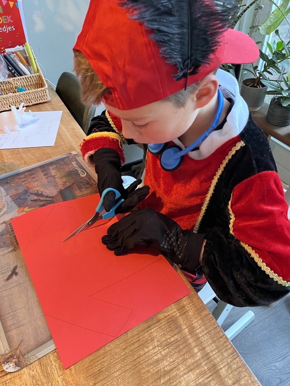 Kind in pietenpak knipt een letter uit voor een Sinterklaas surprise