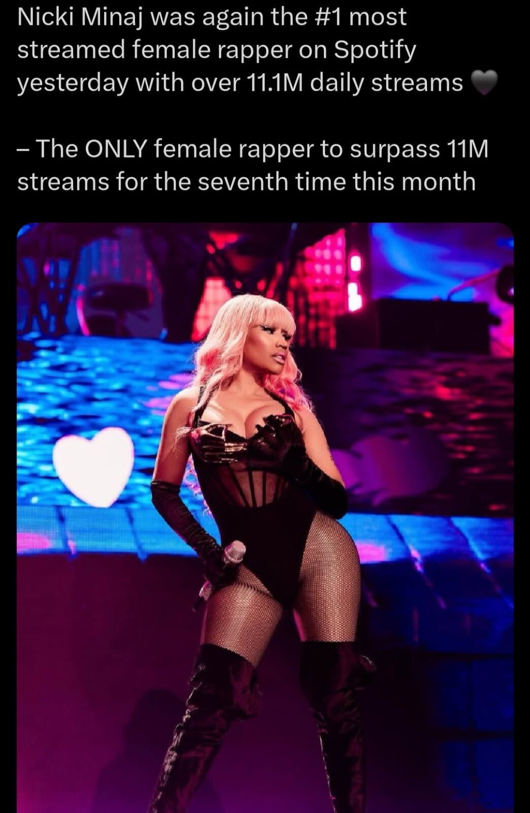 Nicki Minaj performing live on stage in a black bodysuit and thigh-high boots, holding a microphone, as she celebrates surpassing 11.1 million daily Spotify streams in August 2025.