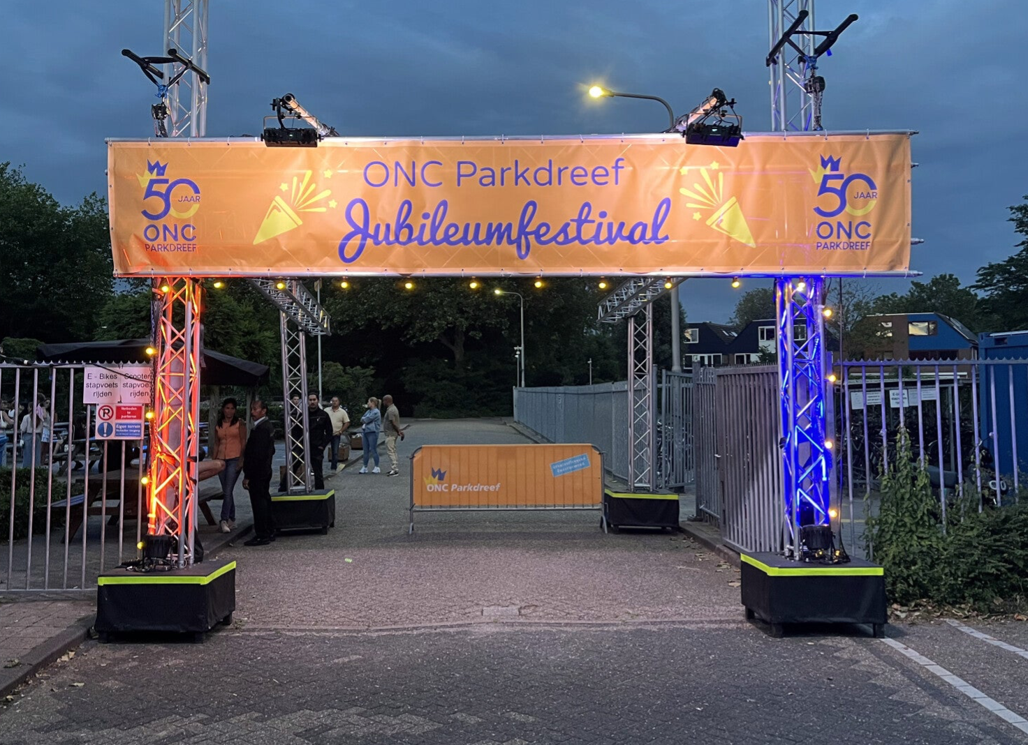 Entreepoort met banner, uitgelicht in een schemerende nacht.
