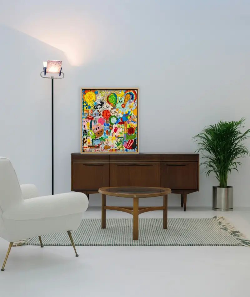 Framed collage made from children’s original artwork displayed on a wooden cabinet in a modern living room.