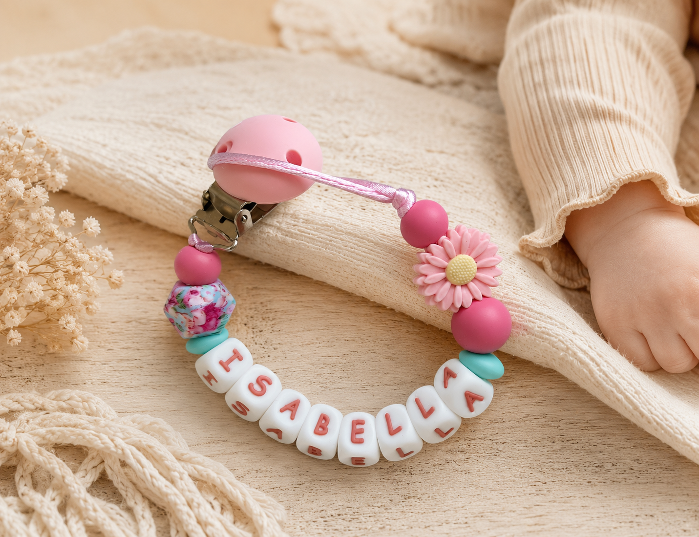 Handgemaakt gepersonaliseerd speenkoord met naam in roze tinten voor baby’s op zachte beige achtergrond