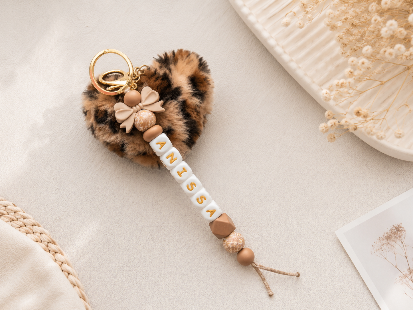 Handgemaakte gepersonaliseerde tassenhanger met naam voor kinderen aan roze rugzak op warme beige achtergrond