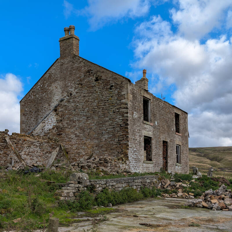 Side of Red Grooves House near Newbiggin, with the remains of adjoining farm buildings, fallen masonry and an exposed stone gable wall.