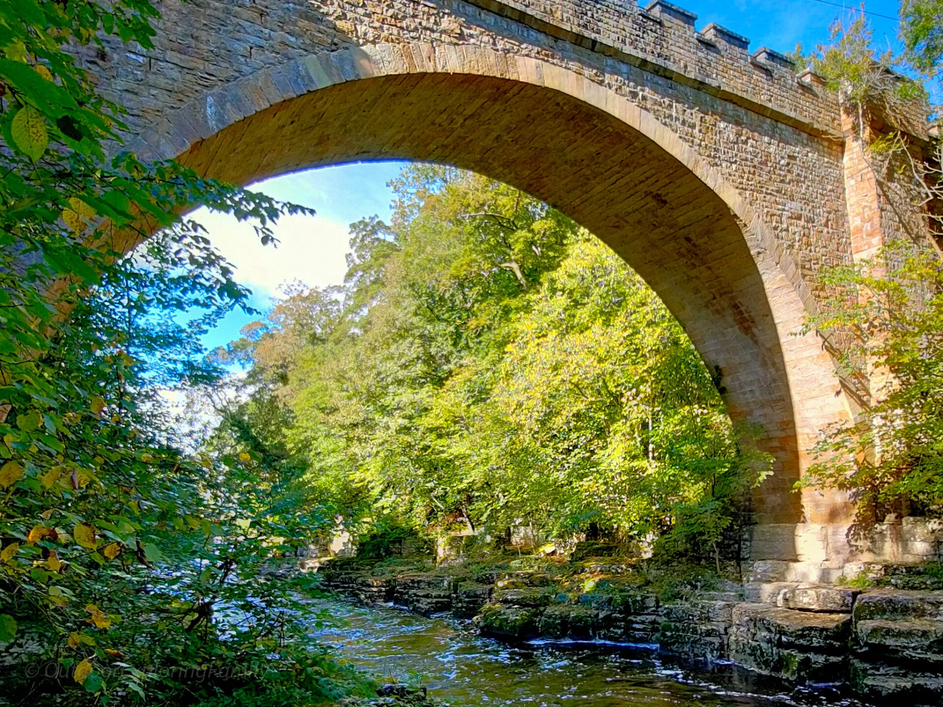 Close view of the historic stone arch and battlemented parapet of Abbey Bridge above the River Tees.