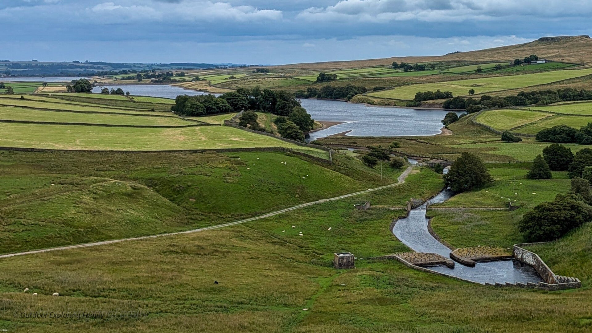 Water flowing from Balderhead Reservoir towards Blackton Reservoir, with winding channels, stone structures and rolling Baldersdale countryside.