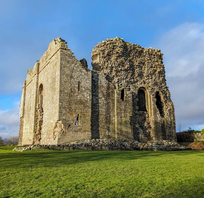 Bowes Castle standing above the village of Bowes in Teesdale, County Durham, with the remains of the medieval keep illuminated by afternoon sunlight.