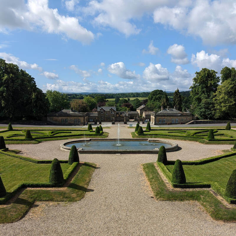 View across the formal gardens and fountain at The Bowes Museum in Barnard Castle with landscaped grounds and Teesdale countryside beyond.
